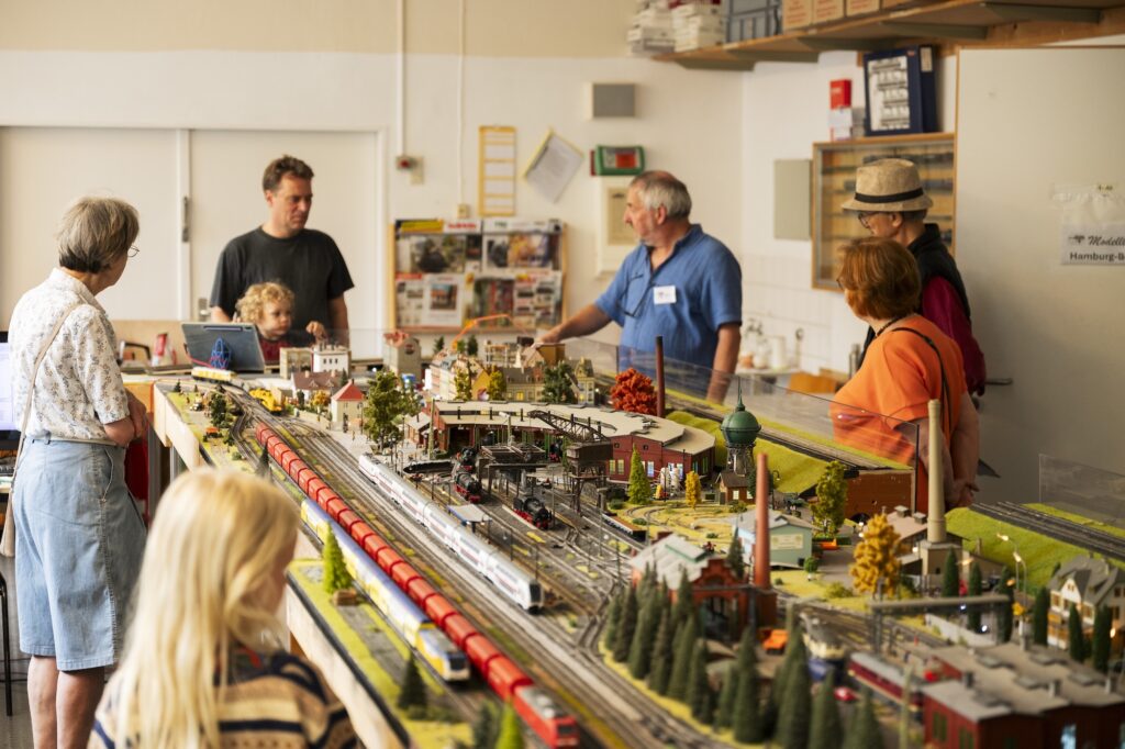 Erwachsene und Kinder betrachten eine Modellbaulandschaft.